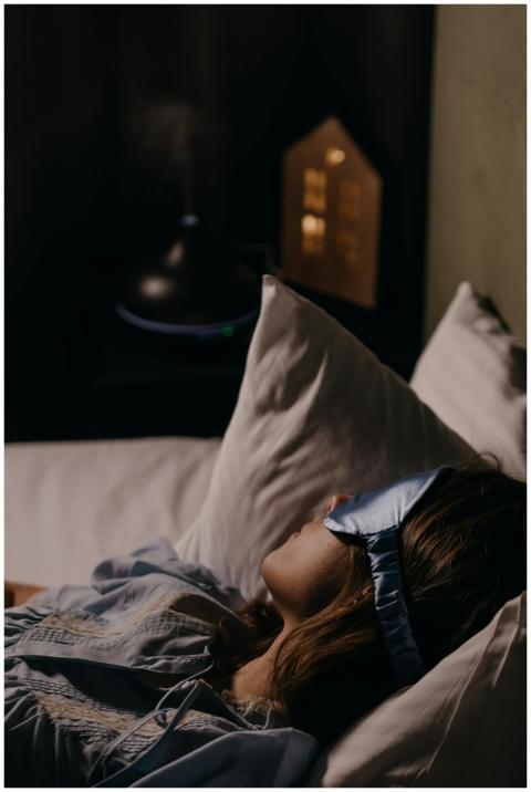 A woman wearing a blue eye mask sleeping comfortab