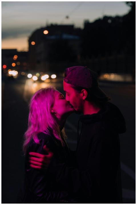 A young couple shares a tender kiss on a city side