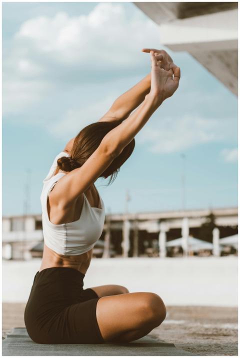 Woman performing yoga stretches outdoors on a mat,