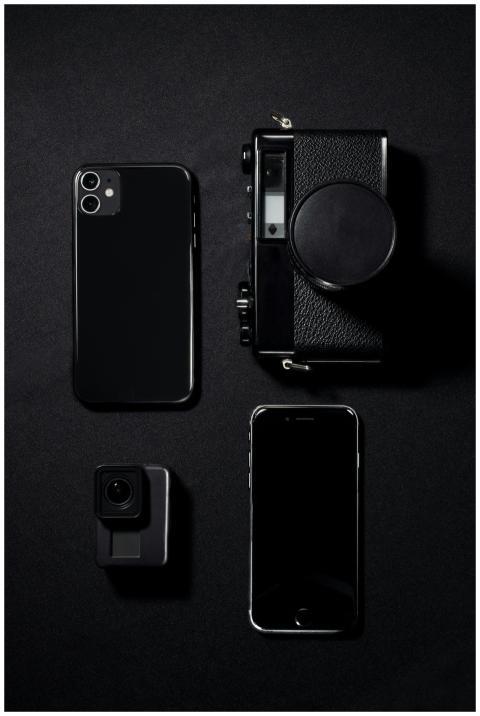 Minimalist flat lay of black gadgets including pho