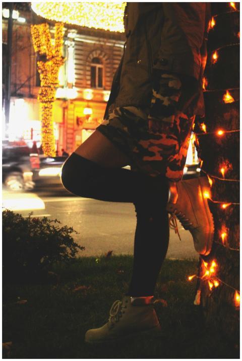 Person standing by tree wrapped in lights, city st