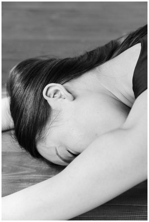 Woman lying on an exercise mat in a tranquil, blac