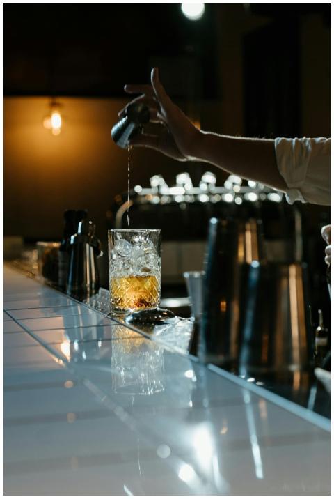 Bartender skillfully pouring whiskey with ice in a