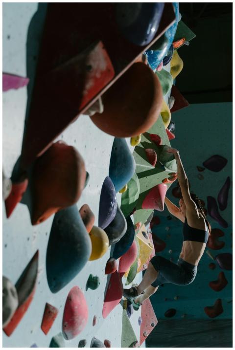Muscular woman rock climbing on an indoor wall wit