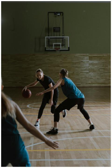 Women basketball players competing on an indoor co