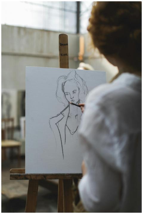 Artist sketching a portrait on canvas in an art st