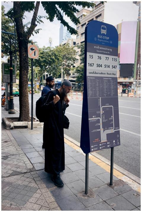 Man reading bus schedule at a Khwaeng Silom bus st