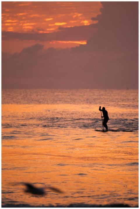 Silhouette of a person paddleboarding during a vib
