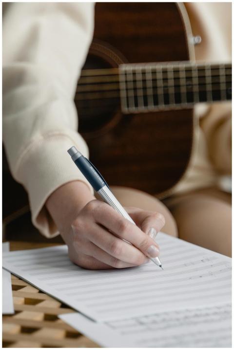 Close-up of a woman writing music notes with guita