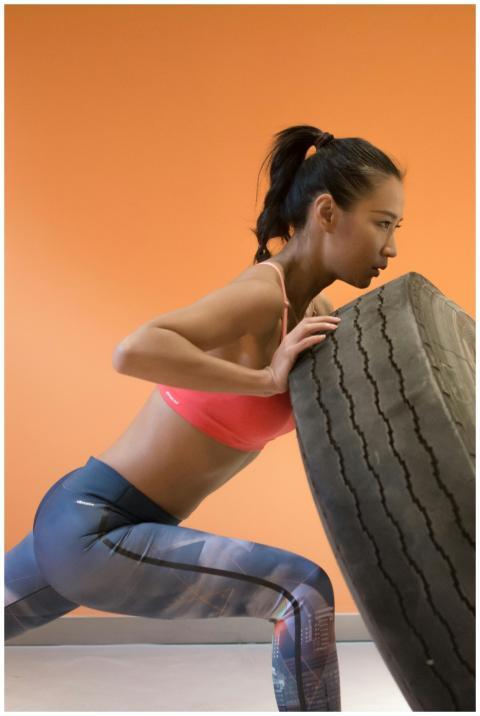 Strong woman pushing tire during gym workout, show