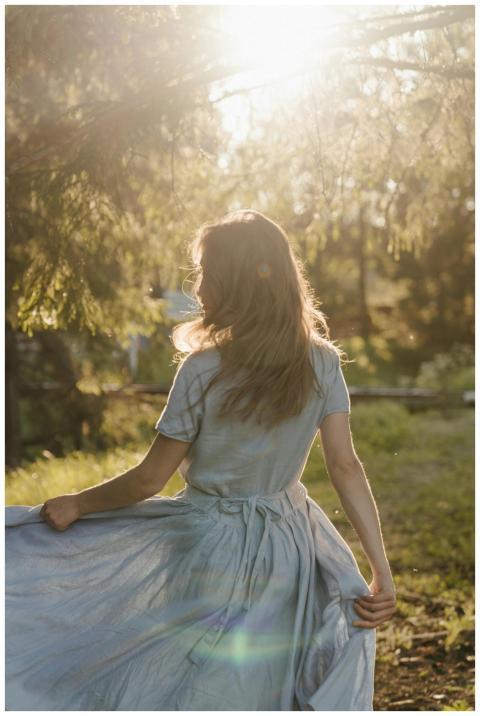 Woman in flowing dress walking through sunlit coun