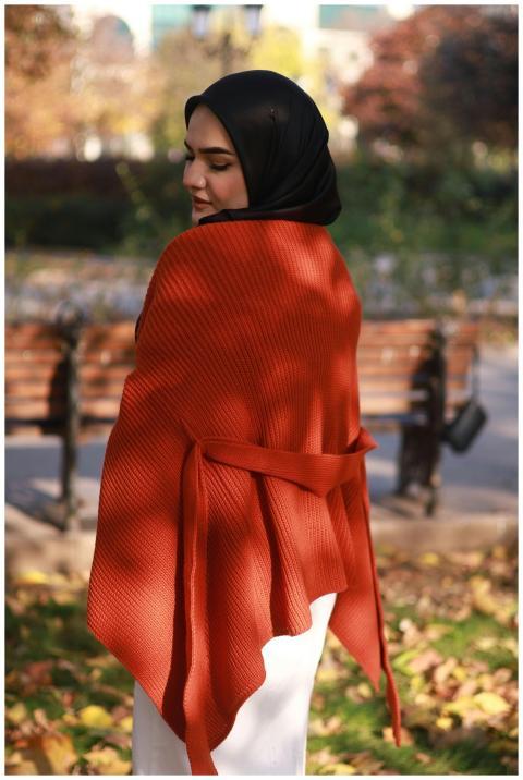 A woman in a hijab and orange shawl standing in a