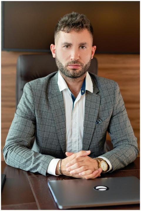 Confident businessman in a suit sits at a desk in