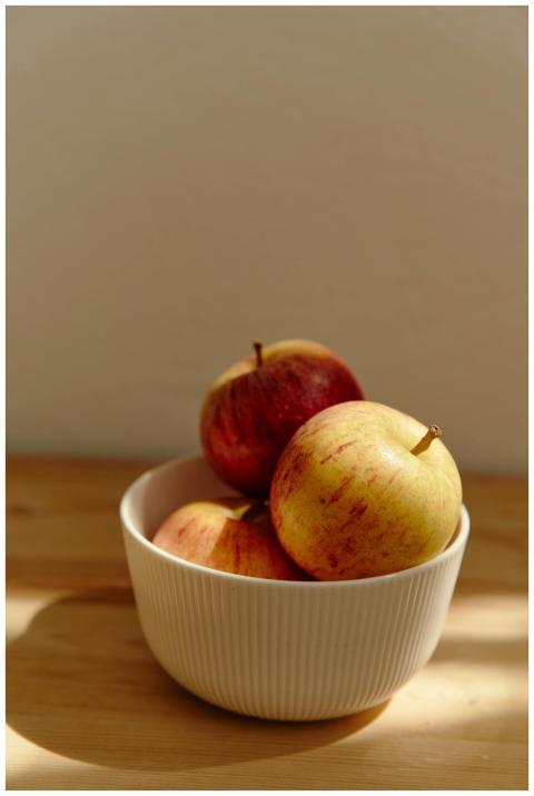 Close-up of red apples in a ceramic bowl on a wood