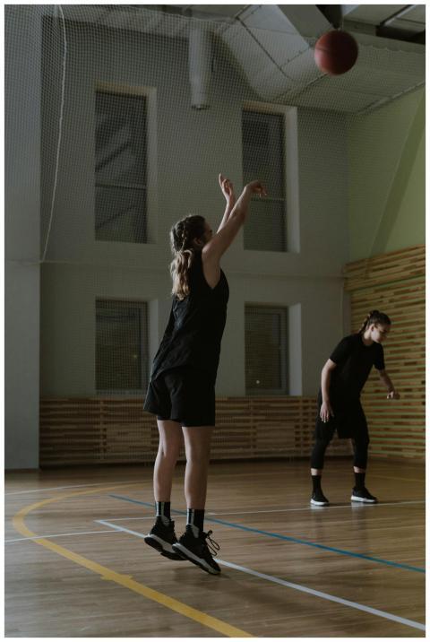 Athletes practicing basketball inside a gym, showc
