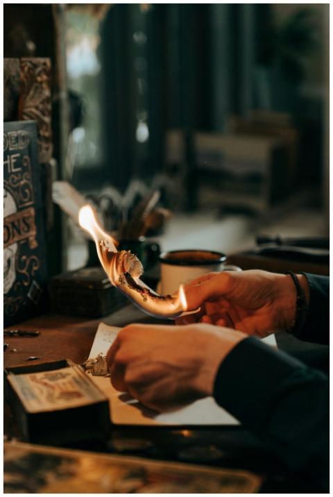 A close-up of hands burning paper amidst artistic