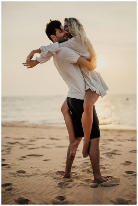 Happy couple embracing on sandy beach at sunset, e