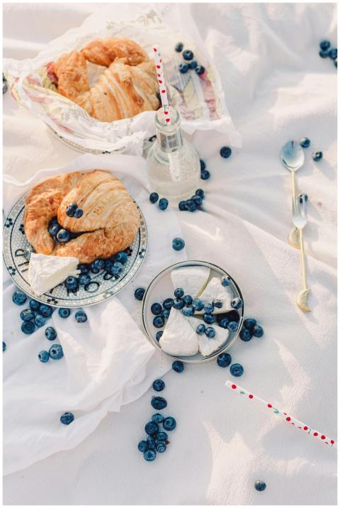 Elegant picnic setup with croissants, blueberries,