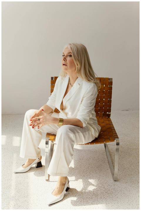 Senior businesswoman in stylish white suit sitting
