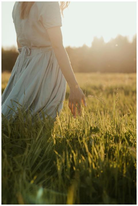 A woman in a light dress walks through a sunlit fi