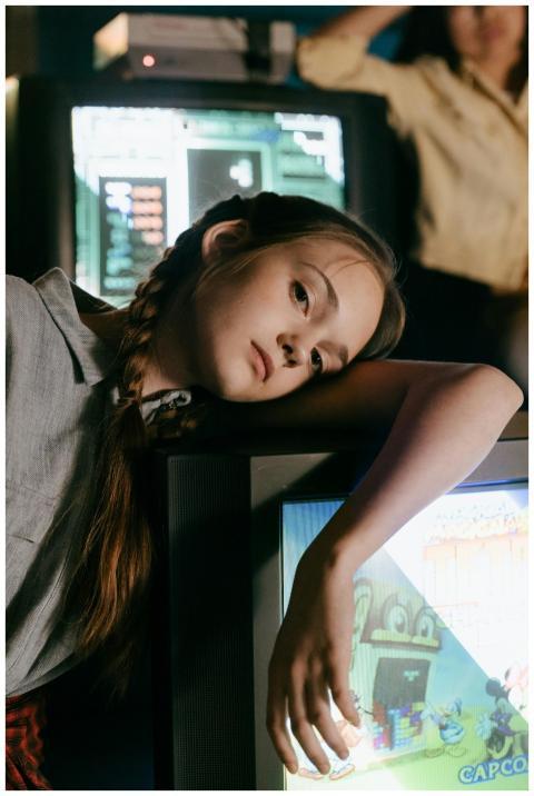 Teen girl with pigtails leans on retro TV in a dim