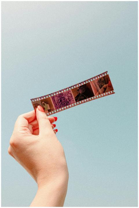 Close-up of a hand holding a film strip against a