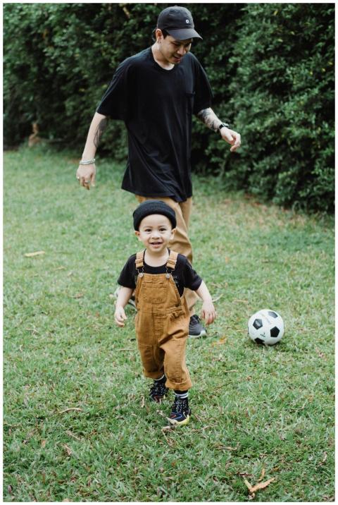 A joyful father and son playing soccer on a sunny