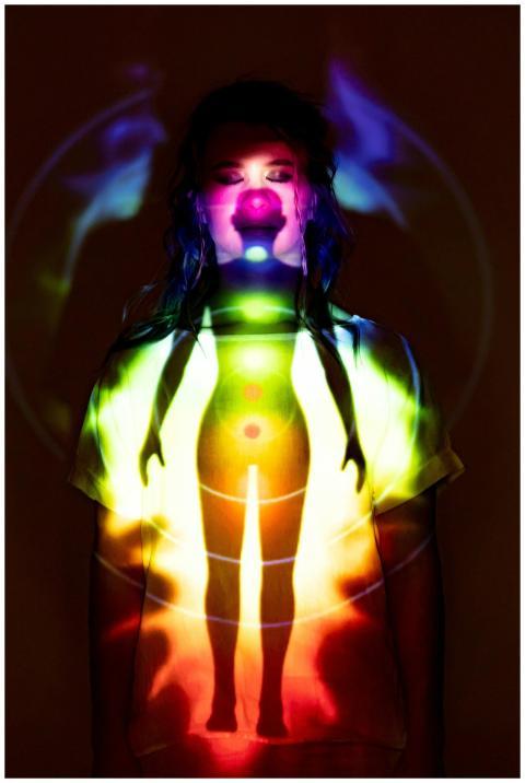 A woman stands in a dark room with a colorful chak