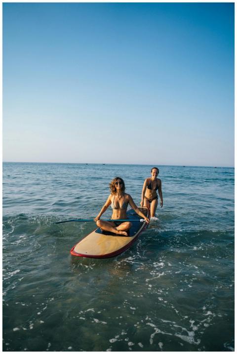 Two women paddleboarding in swimwear on a sunny be