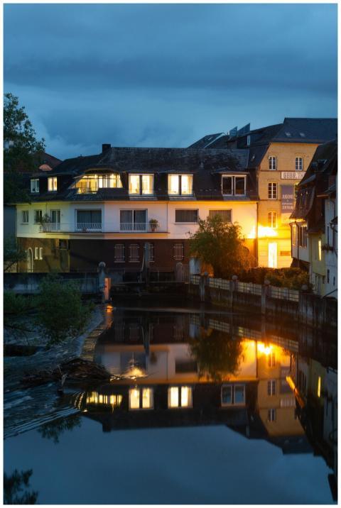 Warmly lit riverside buildings reflecting in water