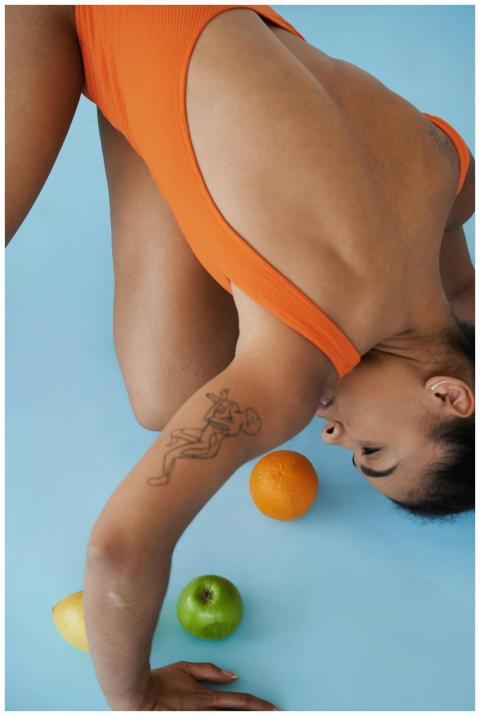 A woman stretches on a blue background with apples