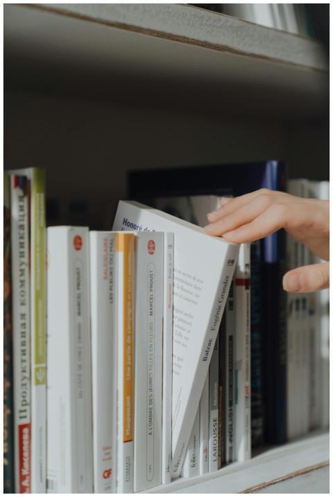Close-up of a hand picking a book from a library s