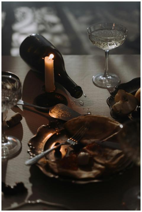 Moody candlelit table with wine bottle, empty plat