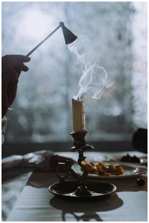 Hand snuffing a candle with elegant candlestick, s