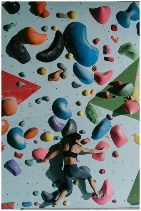 Woman navigating colorful bouldering wall in indoo
