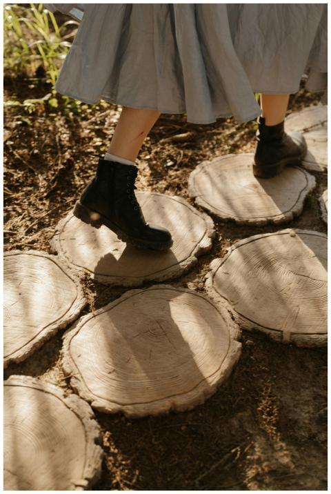 A woman in boots and a dress walking on wooden log