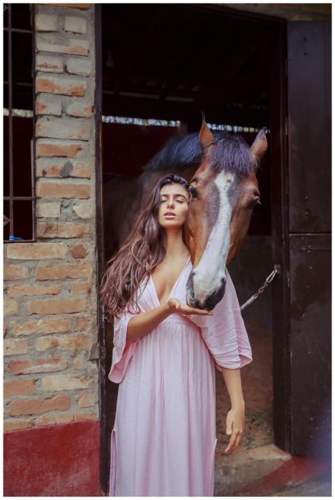 Elegant woman in a pink dress standing with a hors