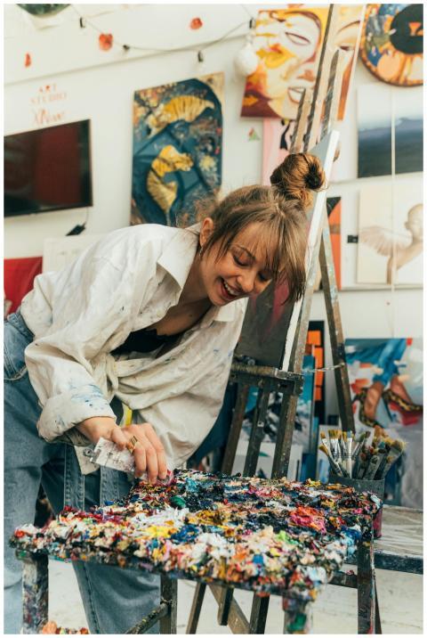 Young woman artist joyfully painting in a vibrant