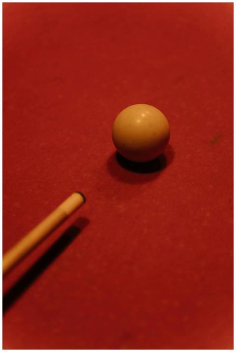 A cue ball positioned on a red billiard table, per