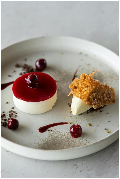 A refined dessert with cherry topping and intricat