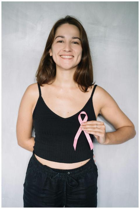 Smiling woman holding a pink ribbon for breast can