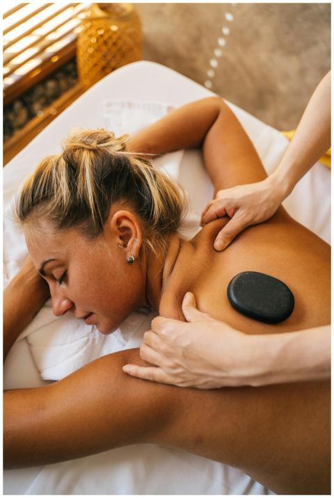 Woman enjoying a hot stone massage at a spa, promo