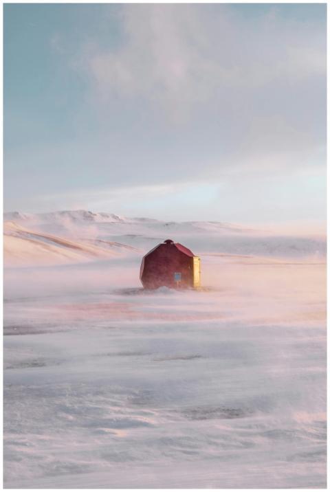 A red cabin stands solitary on a snowy landscape d