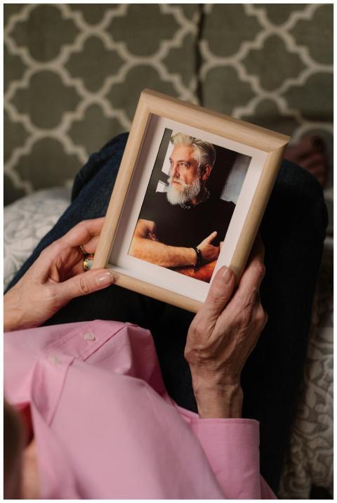 A woman in a pink shirt holds a wooden frame with