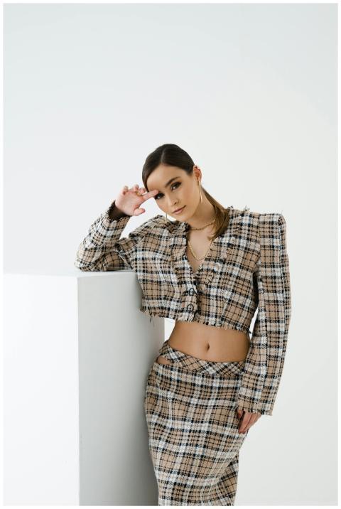 Elegant woman posing in plaid pantsuit on a white