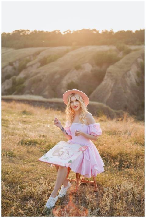 Blonde woman in a pink dress painting outdoors in