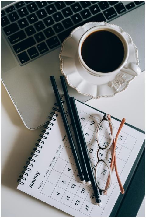 Flat lay of a coffee cup, calendar, and laptop for