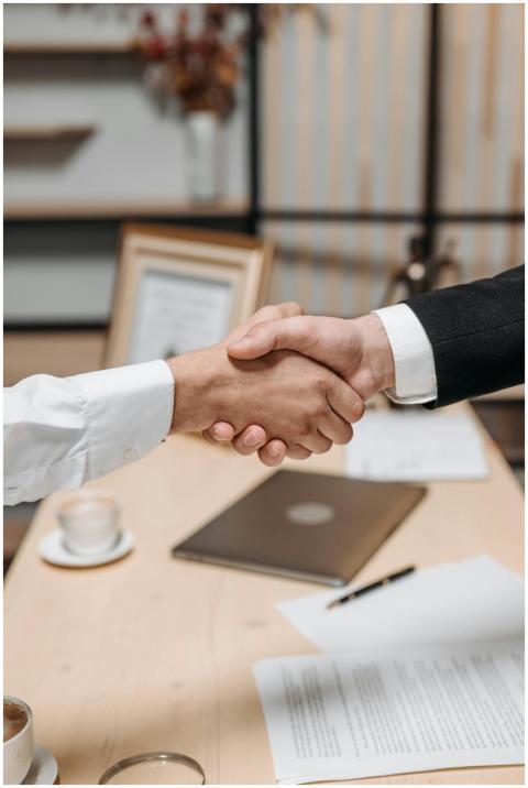 Close-up of two people shaking hands in an office,