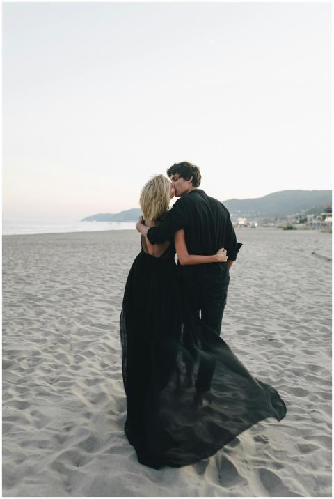A romantic couple embraces on an empty beach at su