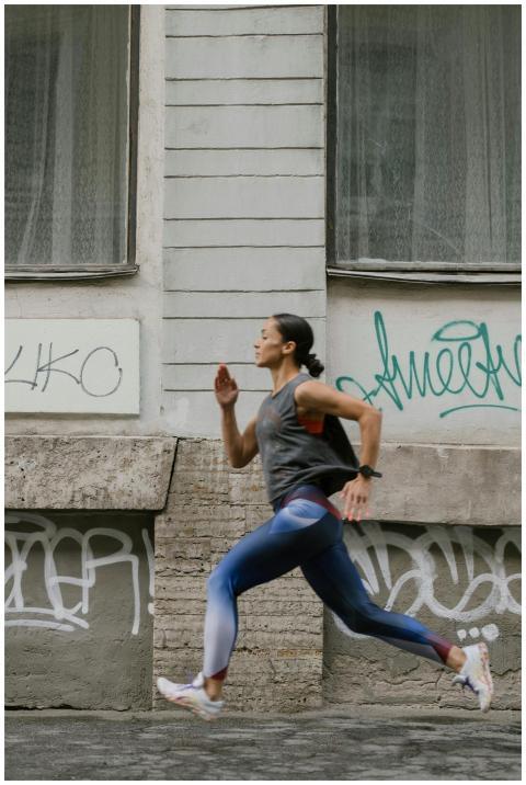 A woman in activewear jogging swiftly past a graff